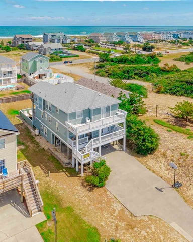 Aerial view of beachfront homes with ocean and sandy dunes in background