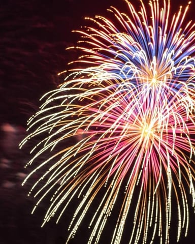 Colorful fireworks bursting in night sky with gold, pink, and blue streaks