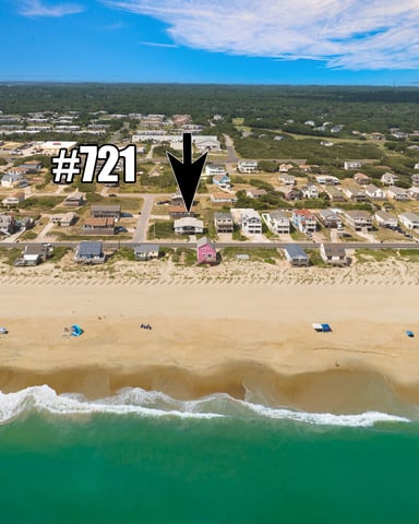 Aerial view of beachfront homes with sandy beach, ocean waves, and dunes marking property #121