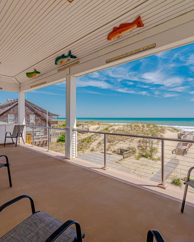 Covered oceanfront porch with lounge chairs, fish decorations on ceiling, beach and turquoise water view