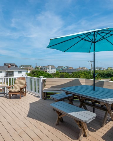 Rooftop deck with turquoise umbrella, picnic table, Adirondack chair, and coastal neighborhood view