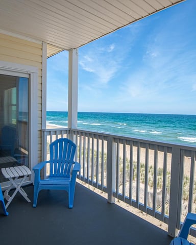 Oceanfront deck with blue Adirondack chairs, white railing, and direct beach and ocean views