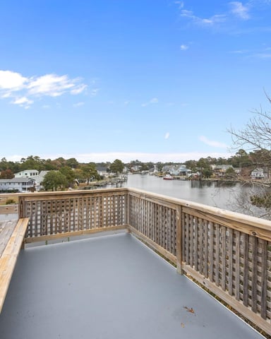 Elevated wooden deck with water view overlooking residential waterfront community and tree-lined shoreline
