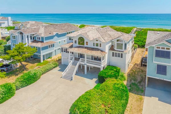 Aerial view of beachfront homes with ocean and sandy beach in background